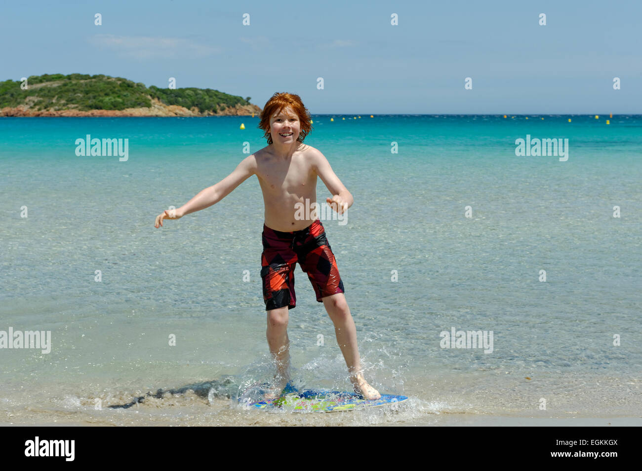 Junge mit seinem Surfbrett, Strand Board oder Skimboarden Surfen, am Strand, Bucht von Rondinara, Südostküste, Korsika, Frankreich Stockfoto