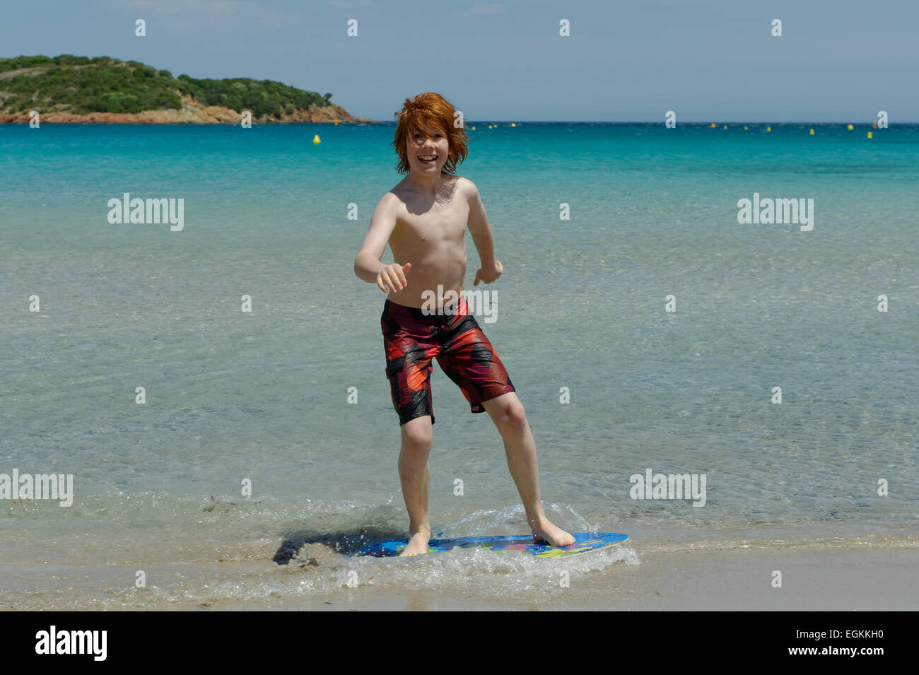 Junge mit seinem Surfbrett, Strand Board oder Skimboarden Surfen, am Strand, Bucht von Rondinara, Südostküste, Korsika, Frankreich Stockfoto