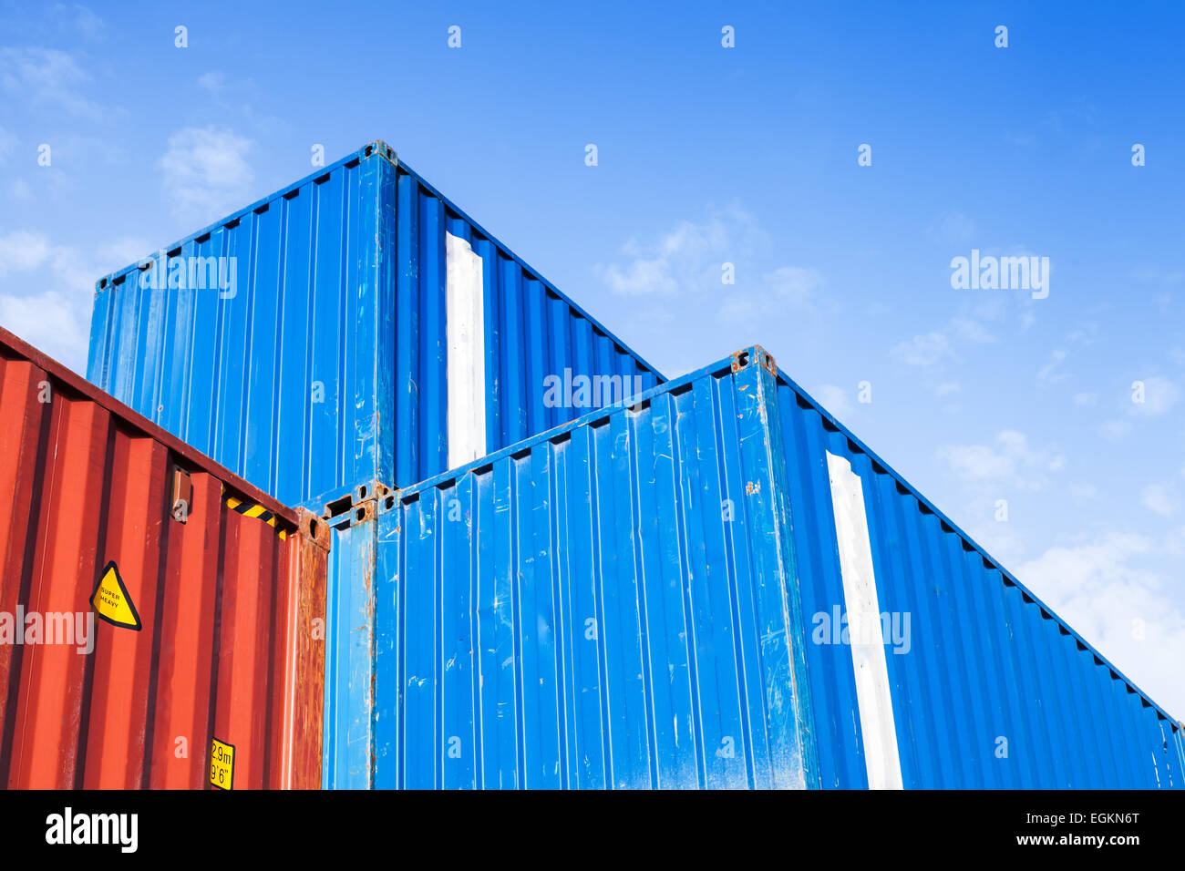 Blaue und rote Metall Industrie Ladungsbehälter gestapelt in den Lagerraum unter blauen Wolkenhimmel Stockfoto