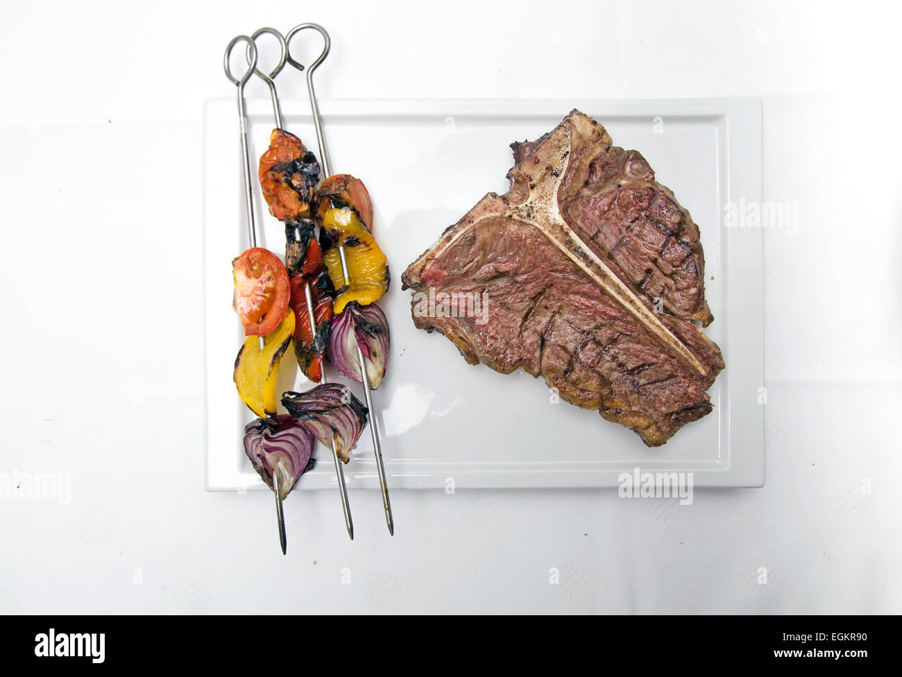 T-bone Steak auf einem weißen Teller mit gegrilltem Gemüse und ein Glas Rot Wein Schuss auf weiß Stockfoto