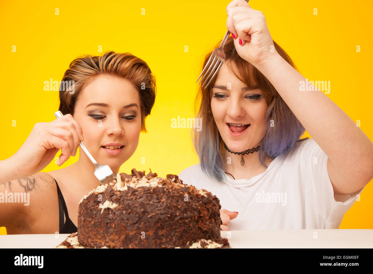 Zwei junge Frau zu einen großen Schokolade Kuchen essen. Stockfoto