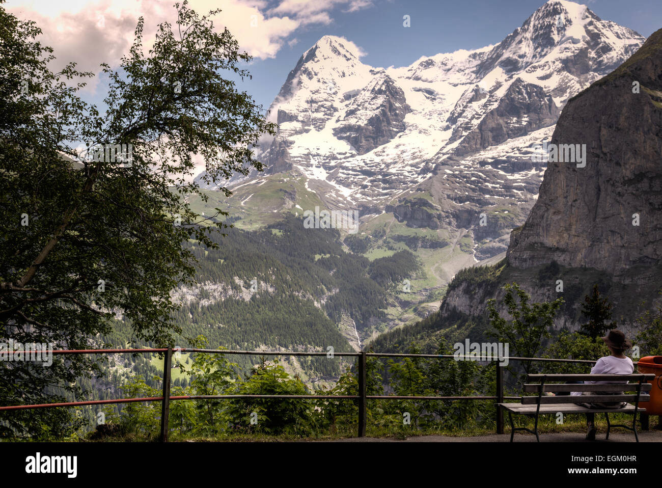 Eine Frau Wanderer sitzt und reflektiert die Schönheit der umliegenden Berge, Tal und Wälder der Schweizer Alpen. Stockfoto