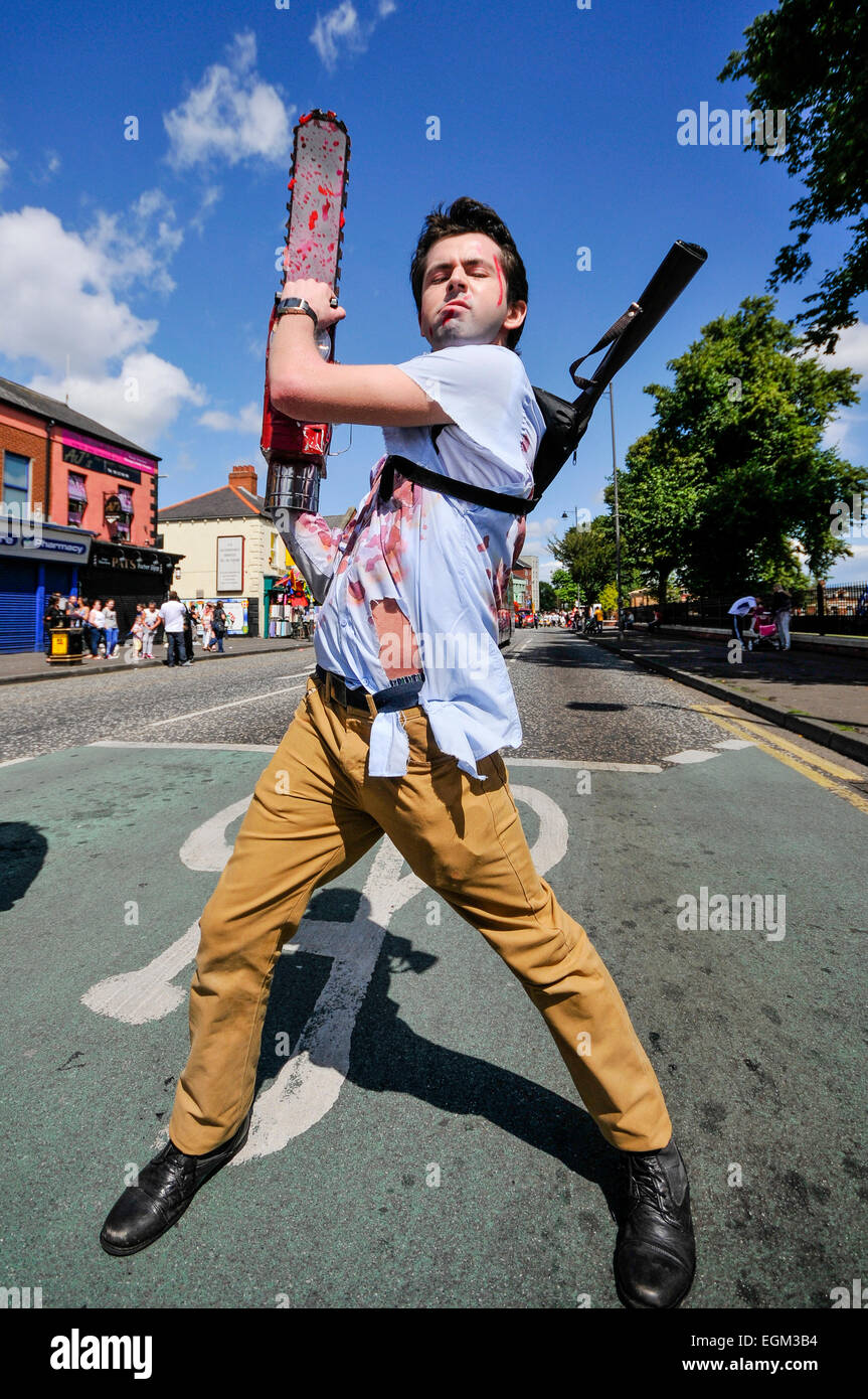 Belfast, Nordirland. 3. August 2014 - ein junger Mann mit "Blut getränkt" Hemd und eine Kettensäge in die Feile eine Phobail (Volksfestes) Öffnung parade Stockfoto