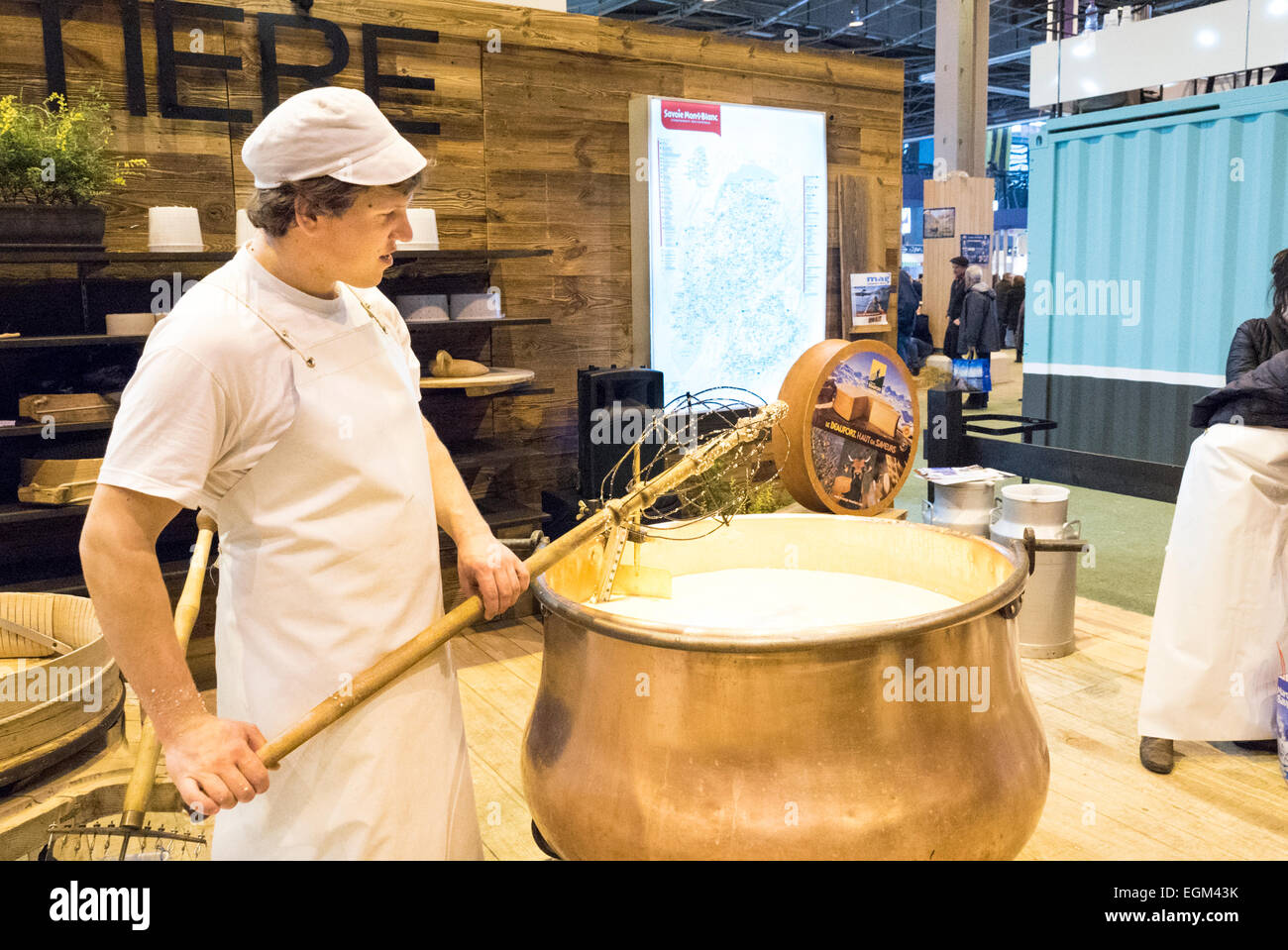 Junger Mann unter einem großen kupfernen Bottich rühren zu Käse in der Landwirtschaft zeigen, Paris, Frankreich, am Mittwoch, 25. Februar, 2015.g Stockfoto