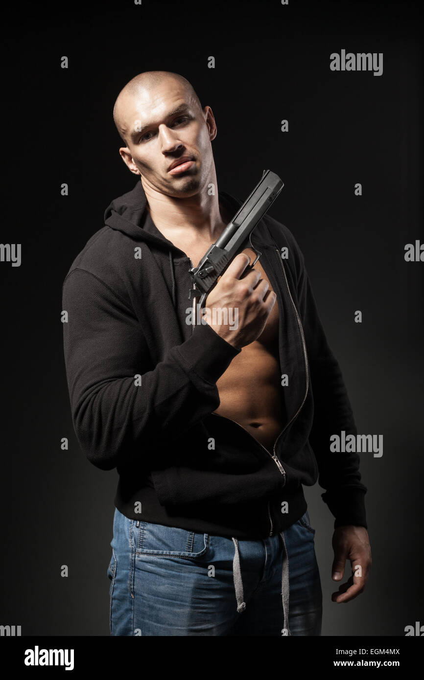 männliche Gangster mit einer Pistole auf dunklem Hintergrund isoliert Stockfoto