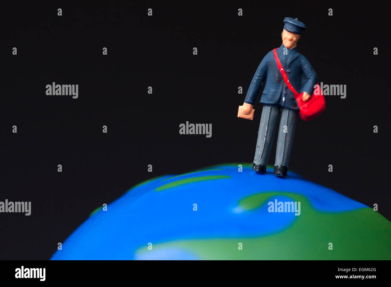 Eine Miniatur Maßstab Modell Figur eines Postboten stehend auf einem Globus. Stockfoto