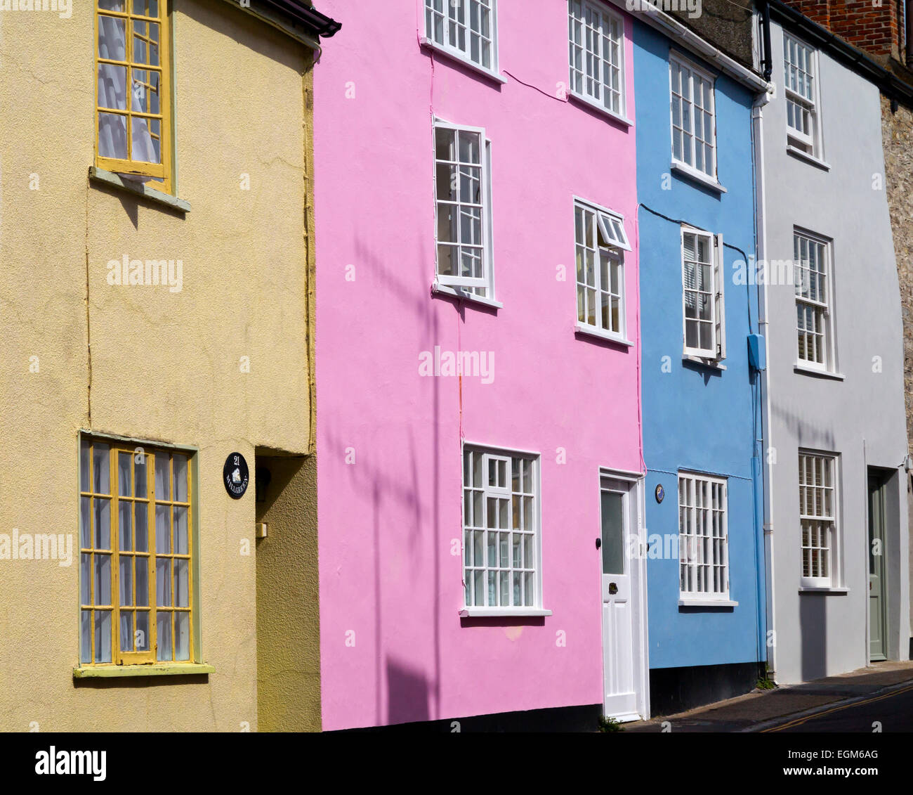 Außen bunt bemalte gelb rosa und blauen Reihenhäuser in einer Straße in Lyme Regis South West England UK Stockfoto