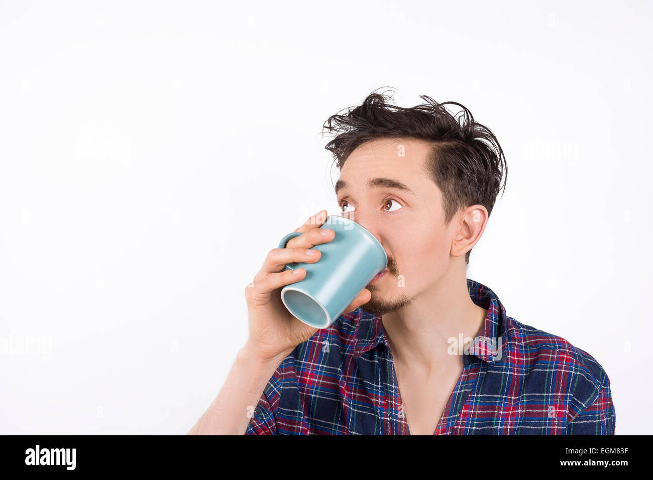 Porträt eines Mannes, der tragenden Pyjamas, Kaffee oder Tee zu trinken und zu seiner rechten suchen. Isoliert auf weiss Stockfoto