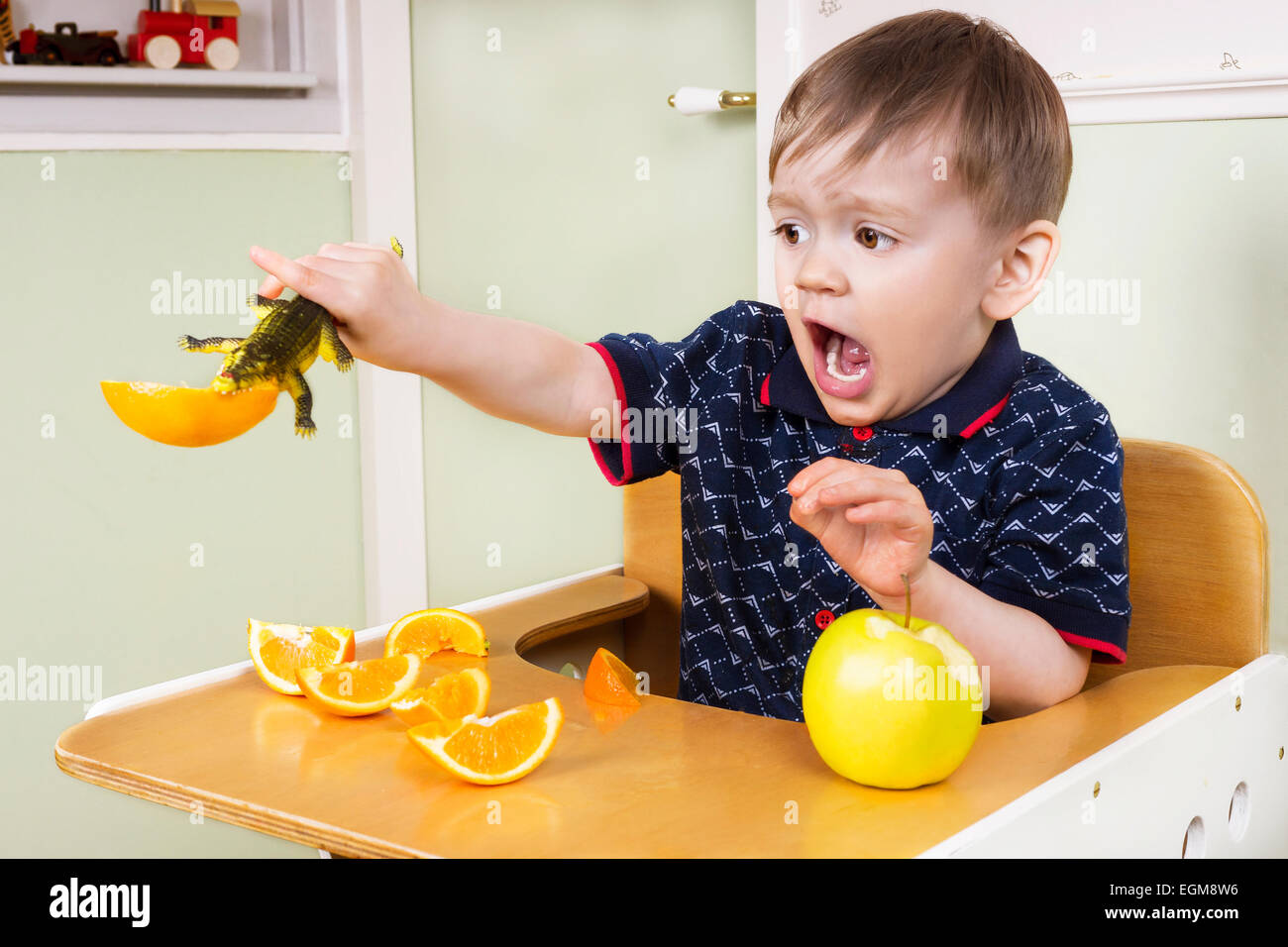 Kleiner Junge Herumspielen mit Obst und handeln albern Stockfoto