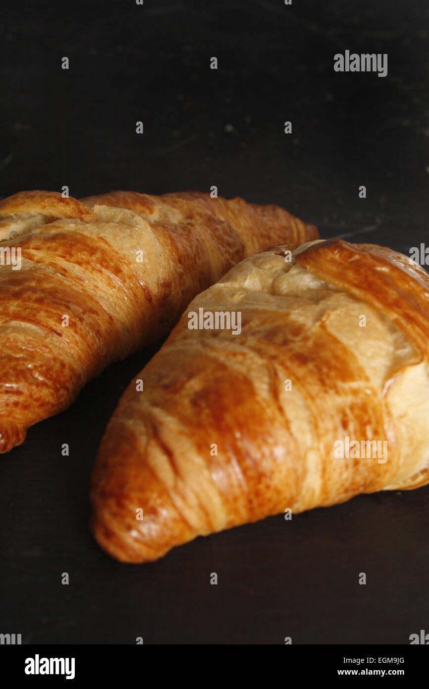 frisch gebackene Croissants auf einem schwarzen Schiefer Stockfoto