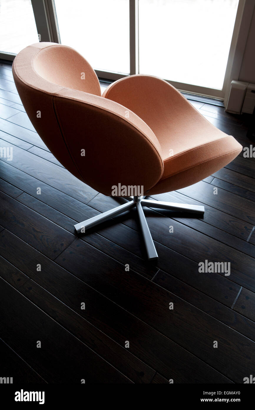 Orange Drehstuhl auf dunklen Holzboden Stockfoto