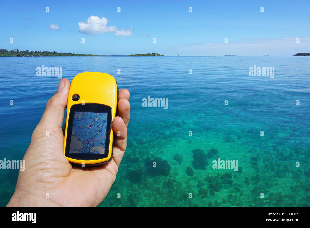 GPS Satelliten-Navigator in der hand, über ruhiges und klares Wasser mit tropischen Insel am Horizont, Karibik, Panama Stockfoto