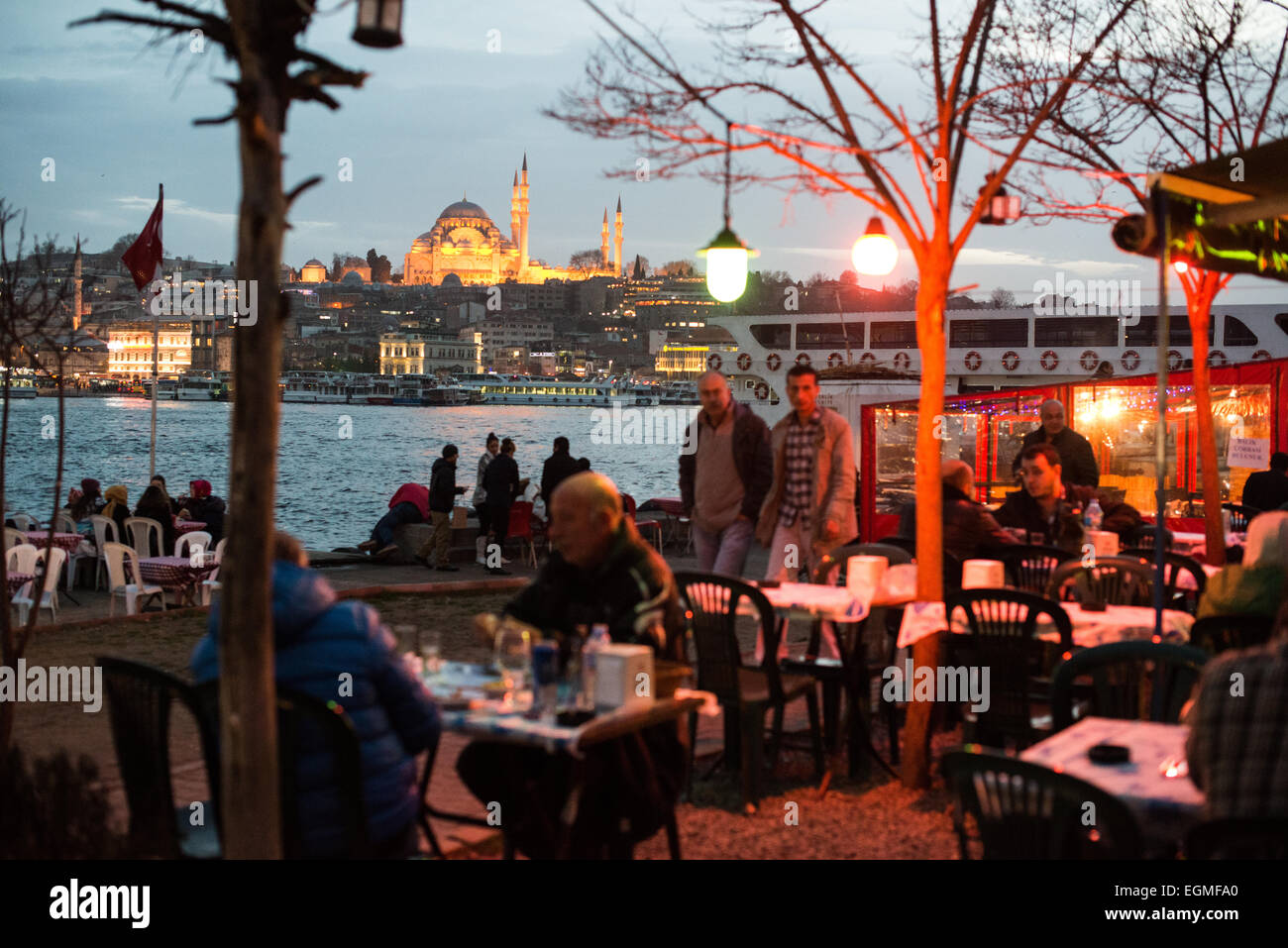 New Mosque Waterfront Restaurants Karakoy Istanbul // ISTANBUL, Türkei – die Gäste genießen ihre Mahlzeiten in Restaurants im Freien am Goldenen Horn in Karakoy, Istanbul. Die historische neue Moschee (Yeni Cami), die 1665 fertiggestellt wurde, und die Galata-Brücke bilden eine dramatische Kulisse. Diese beliebten Restaurants am Wasser bieten frische Meeresfrüchte und traditionelle türkische Küche mit Blick auf die historische Skyline Istanbuls. Stockfoto