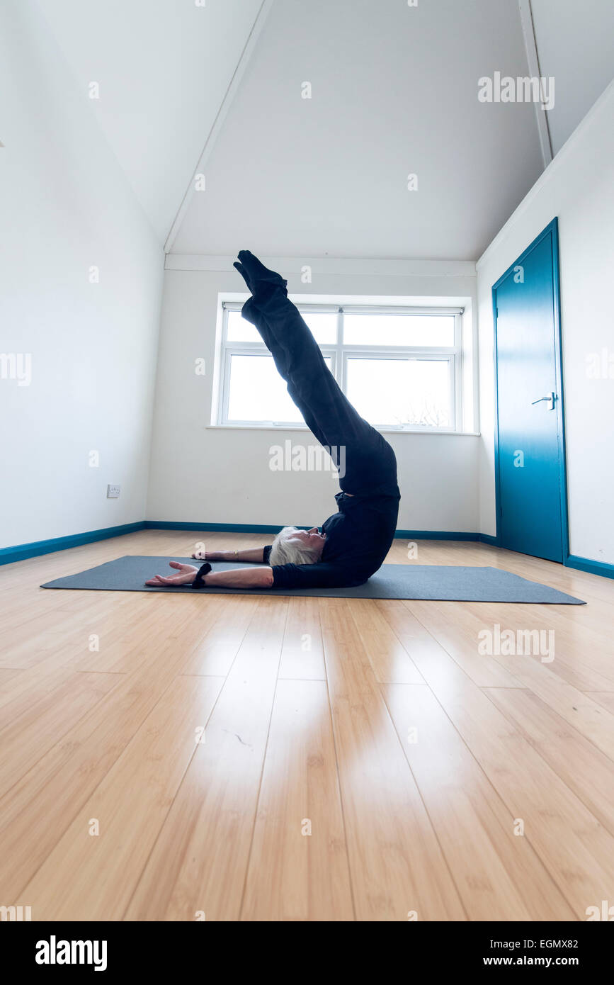 ältere ältere Dame Gaumen Yoga zu praktizieren und dabei sehr flexibel in einigen ungewöhnlichen Positionen aktiv zu halten, Stockfoto