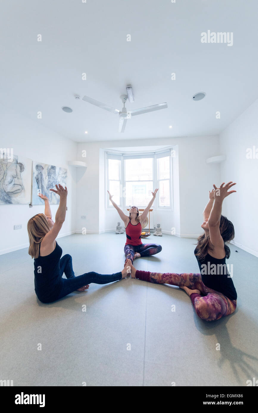 drei Frauen teilhaben in einer Gruppe Yoga Fitness-Klasse, in einem leeren Raum. Die Idee ist, dass Sie sich auf Ihre Partner verlassen Stockfoto