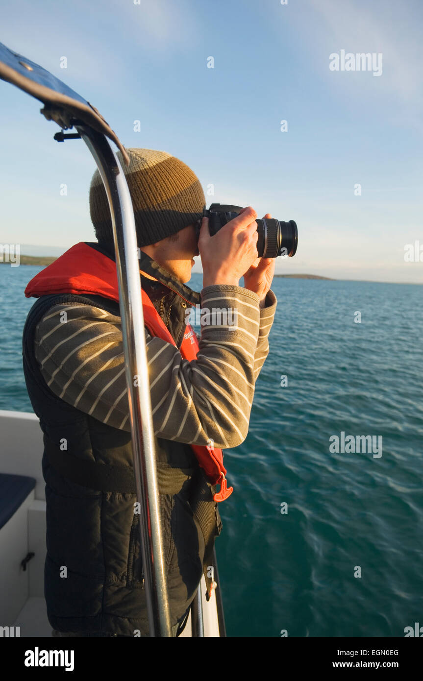Junger Mann mit dem Fotografieren auf einer Bootstour in Scapa Flow, Orkney Inseln, Schottland. Stockfoto