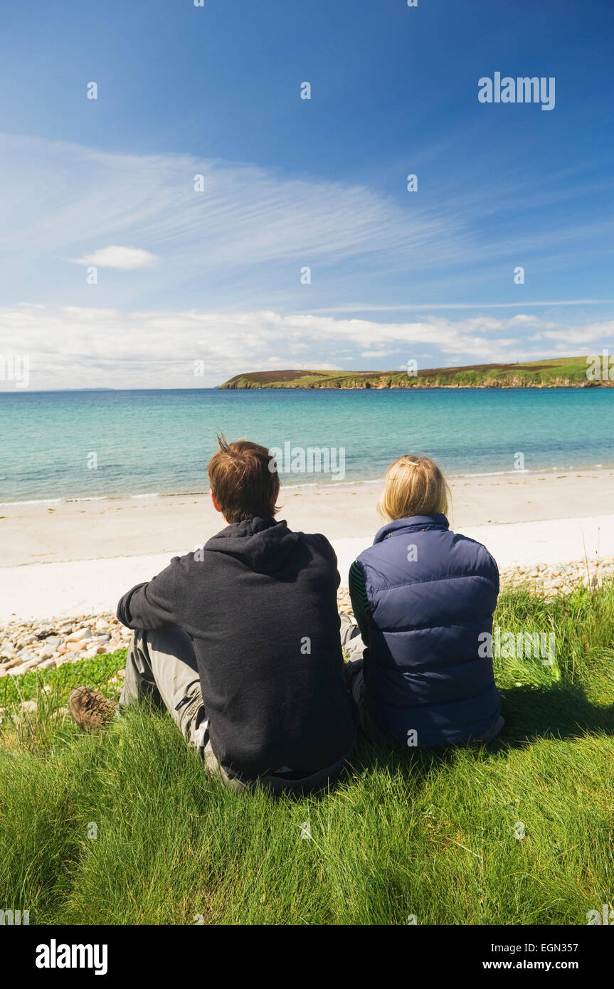 Junges Paar sitzt neben einem schönen Sandstrand, South Ronaldsay, Orkney Inseln, Schottland. Stockfoto