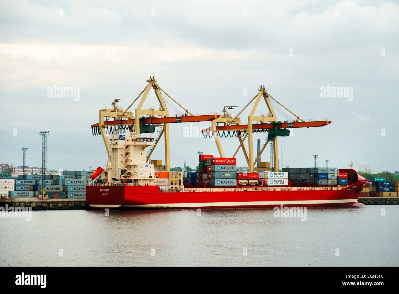 Riga Lettland. Kaufmann Frachtschiffahrt auf Düna Fluss im Freihafen von Riga. Containerschiff Schiff Frederik und dock-Einrichtungen Stockfoto