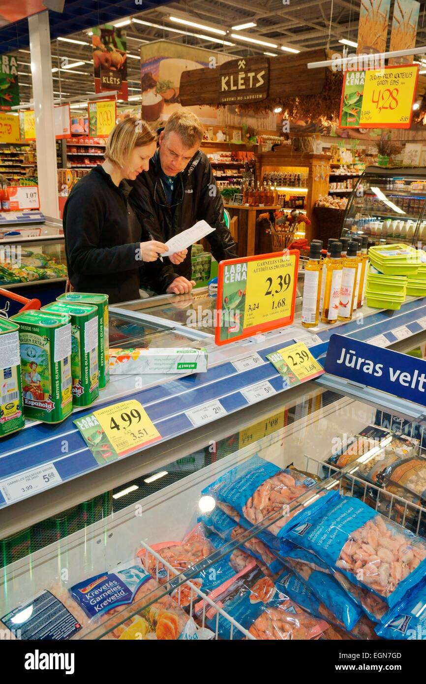 Riga Lettland. Innere des Rimi Hypermarkt lettischen Shop. Kunden zu zweit am Tiefkühlkost Meeresfrüchte Feinkosttheke mit Einkaufsliste Stockfoto