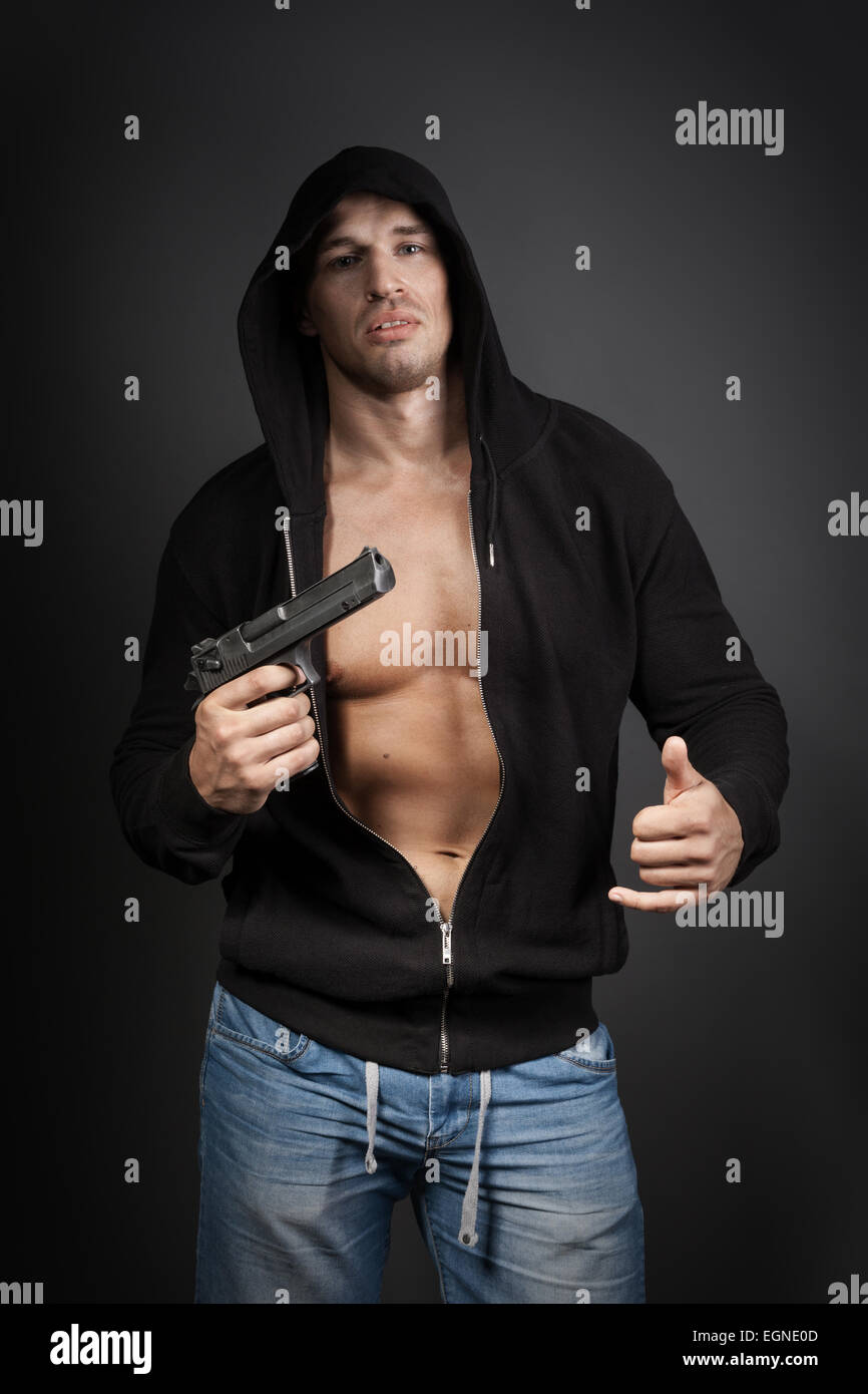 männliche Gangster mit einer Pistole auf grauem Hintergrund isoliert Stockfoto