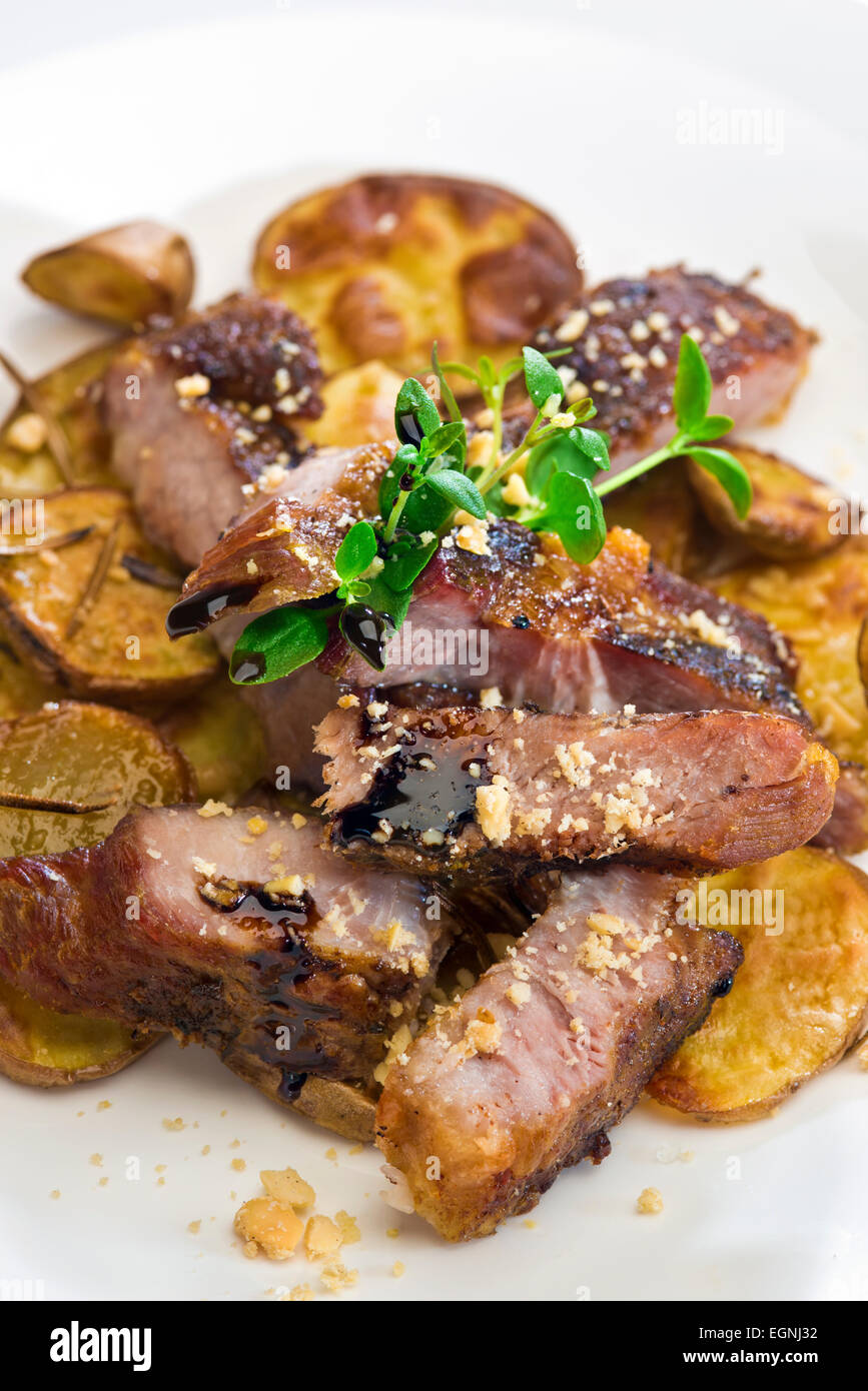 Spanferkel und mit gerösteten Kartoffeln mit Rosmarin, frischer Thymian, Erdnüssen und Balsamico Reduktion Stockfoto