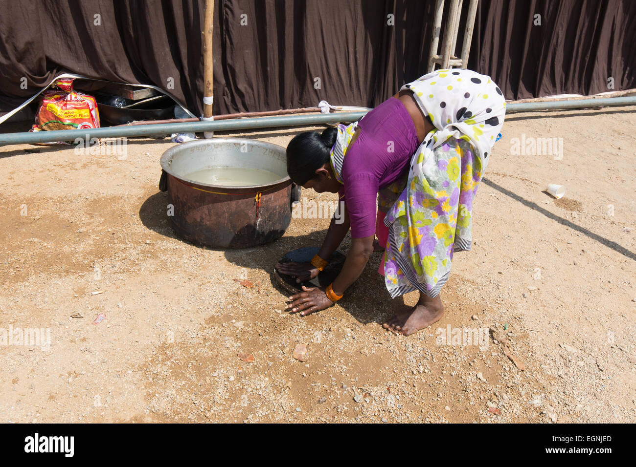 Eine indische Frau wäscht Utensil mit Schlamm Stockfoto