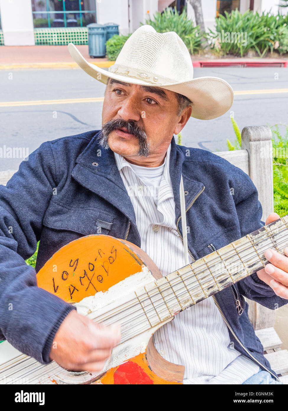 Mexikanische männlichen Gitarrist in weißen Cowboyhut spielen auf einer Bank an der State Street in Santa Barbara, Kalifornien. Stockfoto