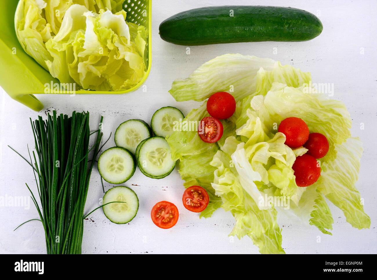 Zubereitung Salat mit Gurken, Salat, Cherry-Tomaten und Schnittlauch auf modernen weißen Holztisch festlegen, über Kopf. Stockfoto