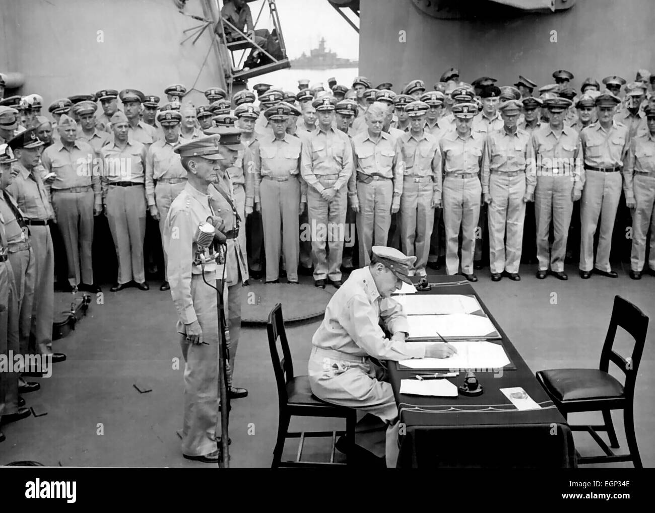 JAPANISCHE Kapitulation General Douglas MacArthur unterzeichnet als alliierte Oberbefehlshaber während der japanischen Kapitulation Zeremonien auf USS Missouri in der Bucht von Tokio, 2. September 1945. Hinter ihm stehen US-General Jonathan Wainwright und britische General Arthur Percival. Stockfoto