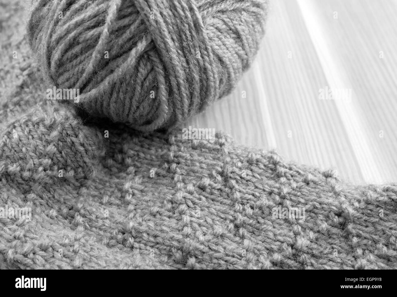 Verarbeitung von gemusterten stricken mit Wollknäuel auf Holztisch - Monochrom Stockfoto