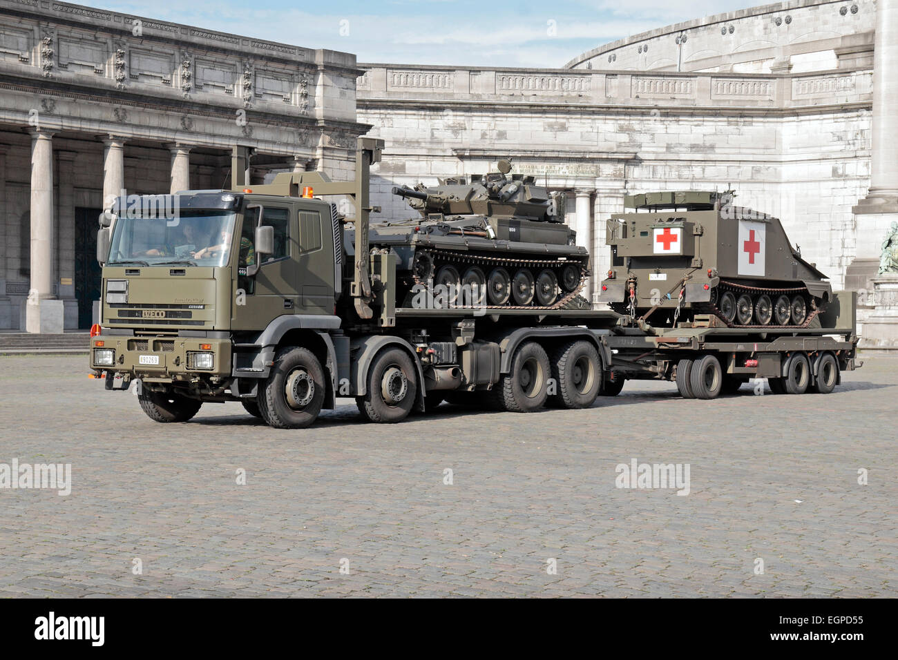Ein IVECO Eurotrakker tank Transporter mit einem leichten Panzer (Alvis Skorpion?) und verfolgt medizinische Fahrzeug in Brüssel, Belgien. Stockfoto