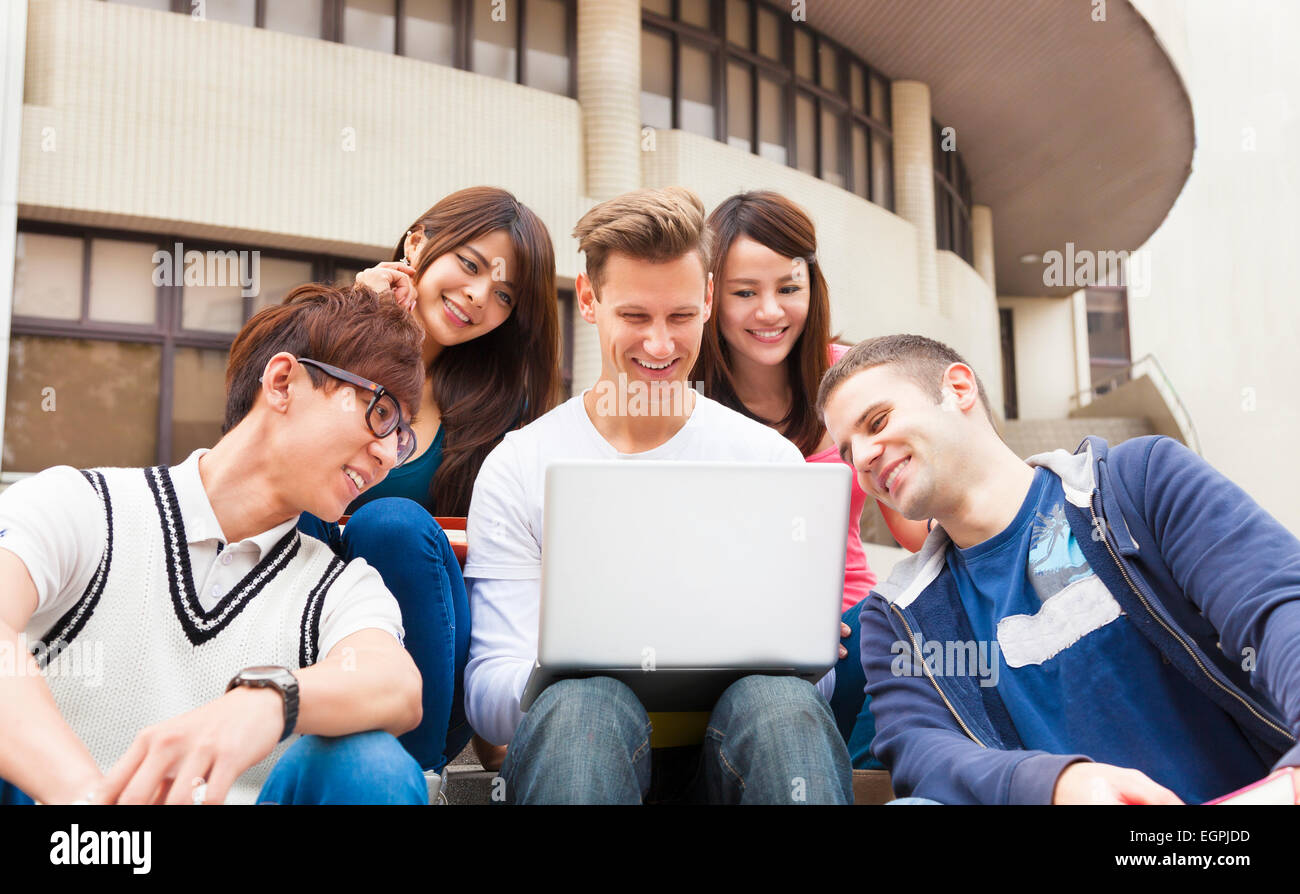 Glückliche junge Gruppe von Studenten, die gerade des Laptops Stockfoto