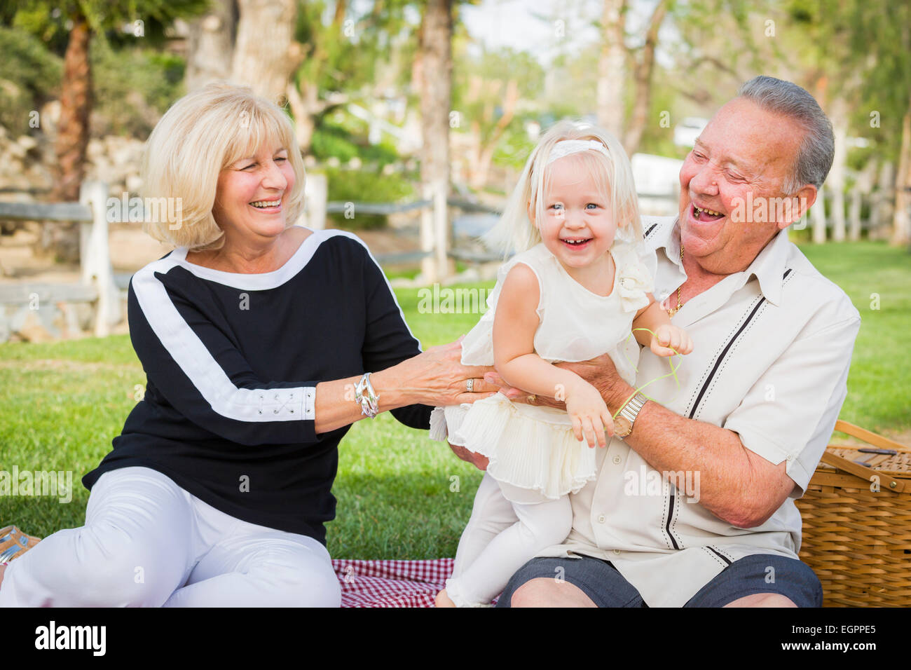 Liebevolle Enkelin und Großeltern spielen draußen im Park. Stockfoto