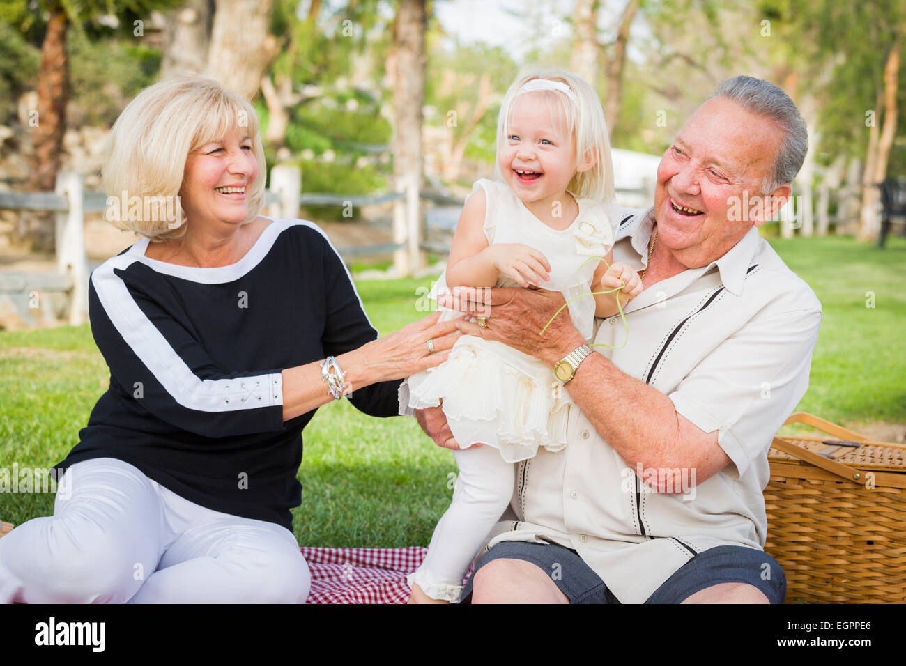 Liebevolle Enkelin und Großeltern spielen draußen im Park. Stockfoto