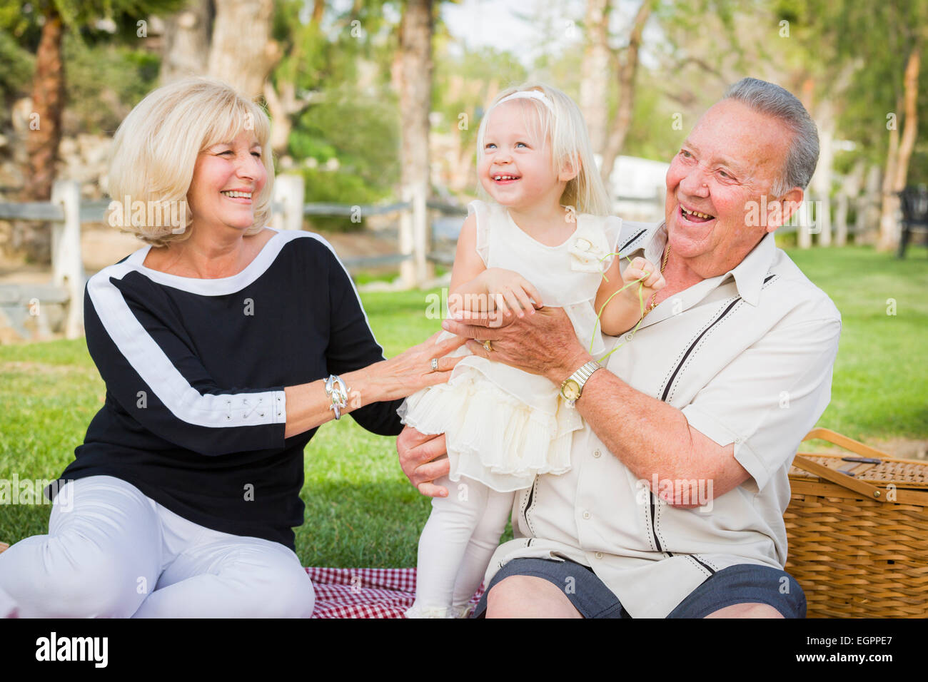 Liebevolle Enkelin und Großeltern spielen draußen im Park. Stockfoto