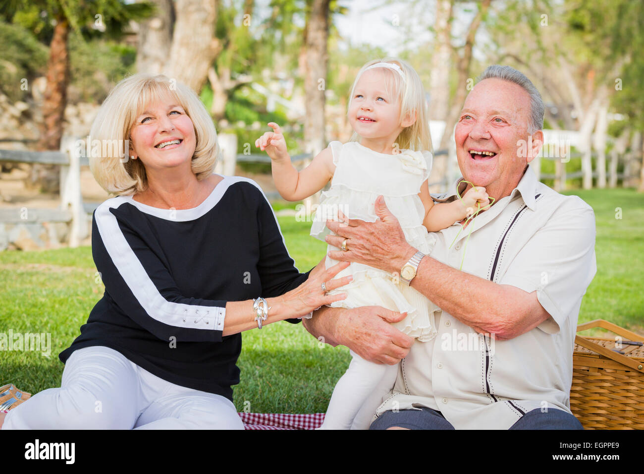 Liebevolle Enkelin und Großeltern spielen draußen im Park. Stockfoto
