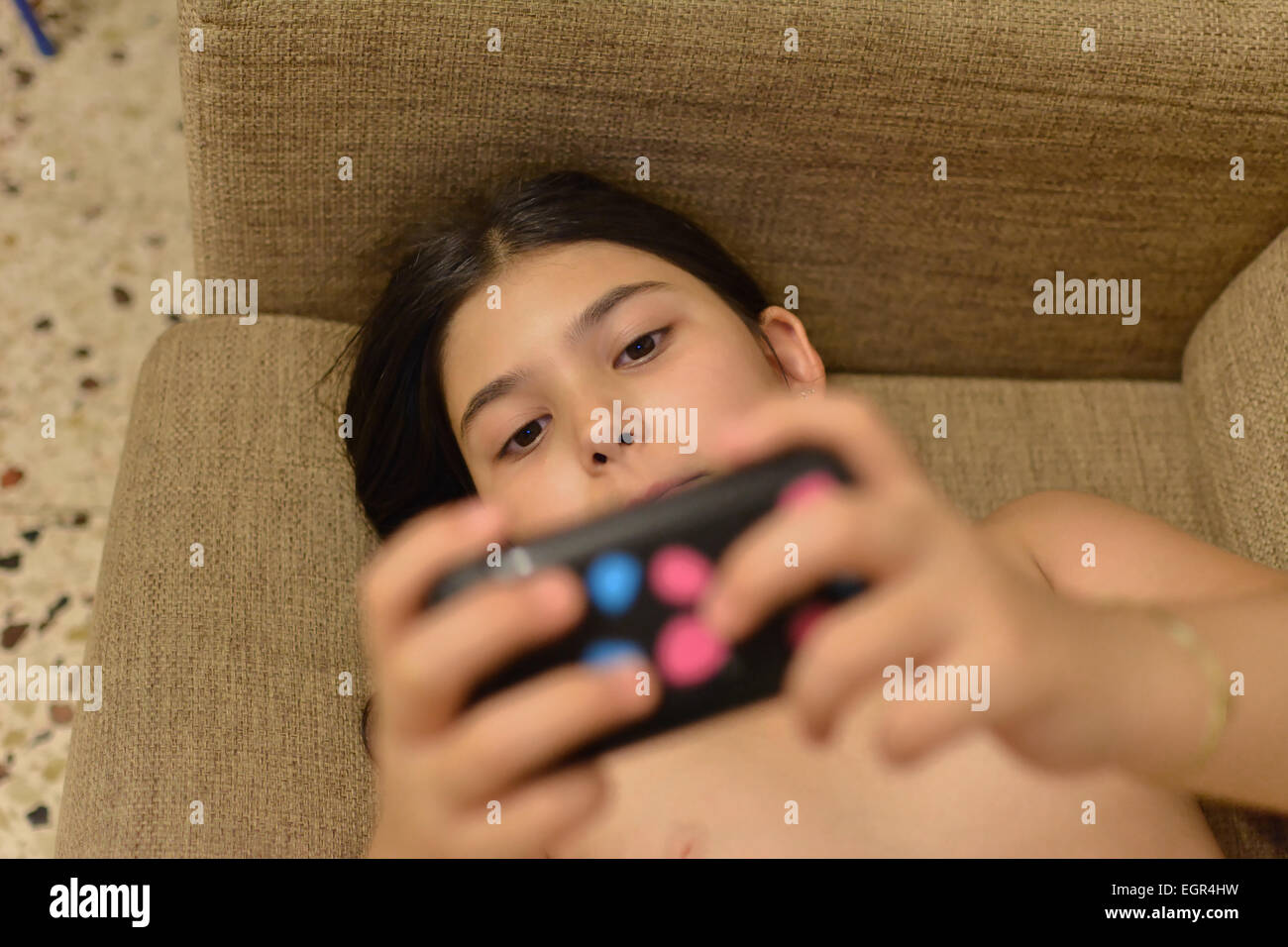 Junges Mädchen spielt Videospiele mit einem handheld-Spielkonsole-Modell veröffentlicht Stockfoto
