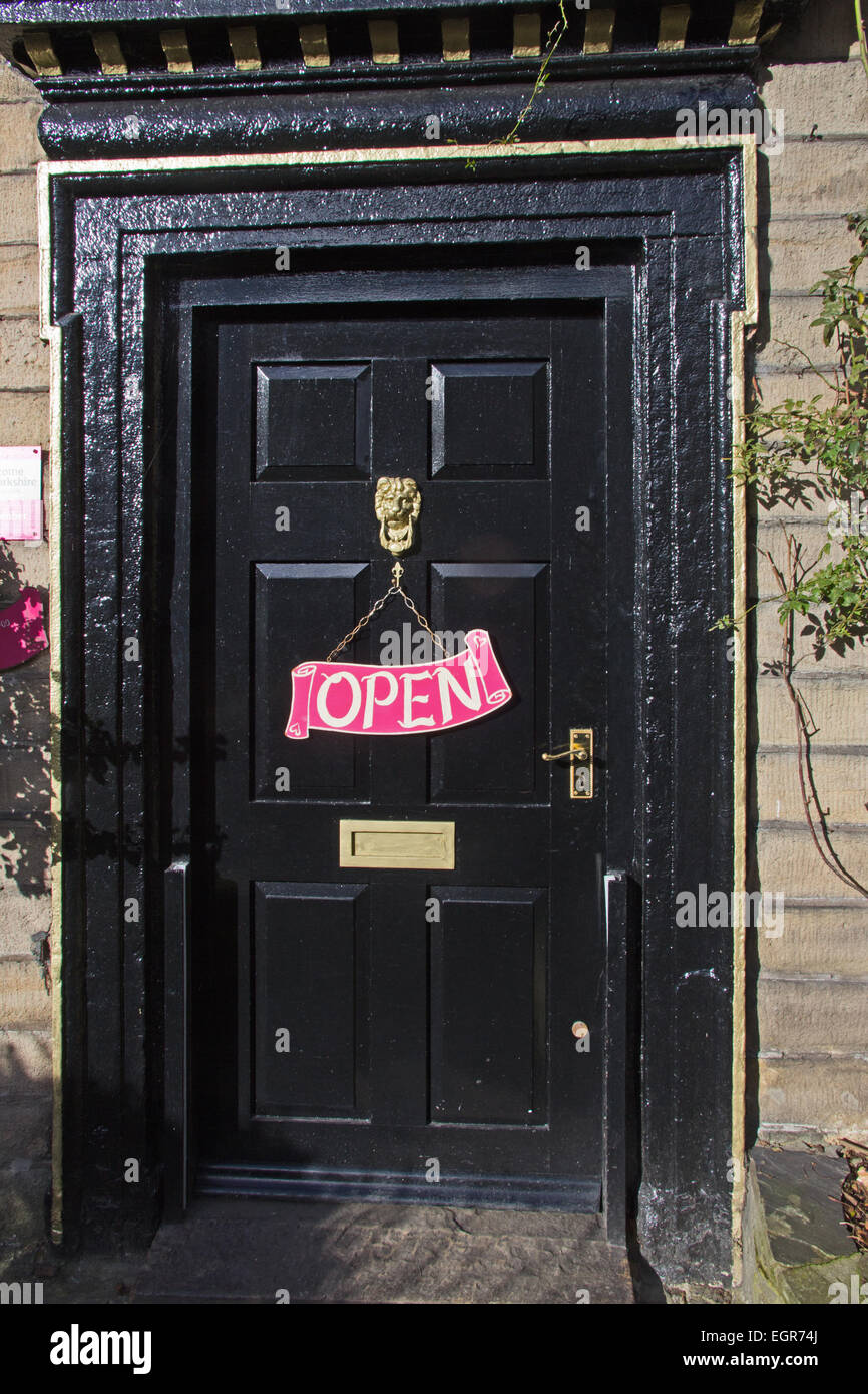 Rosa Schild "geöffnet" am schwarzen Tor. Stockfoto