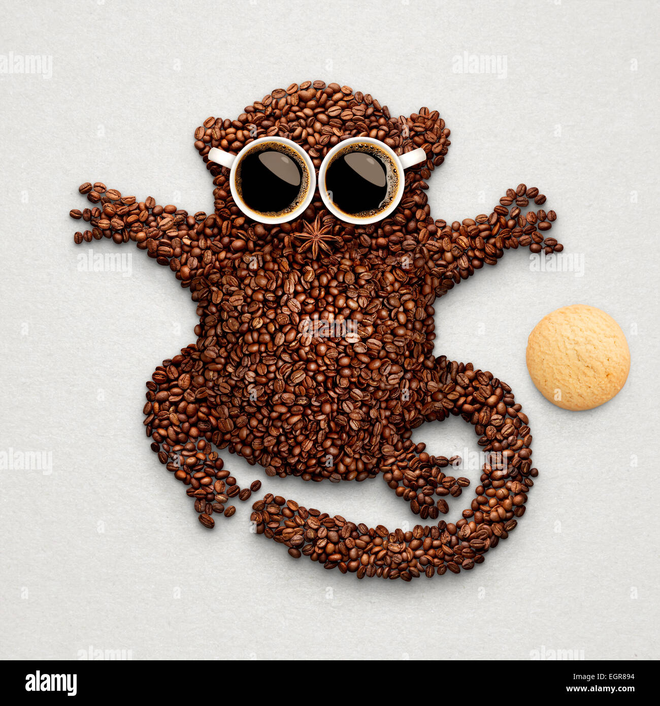 Eine lustige Koboldmaki hergestellt aus gerösteten Kaffeebohnen, zwei Tassen und Sternanis mit einem Haferflocken Cookies. Stockfoto