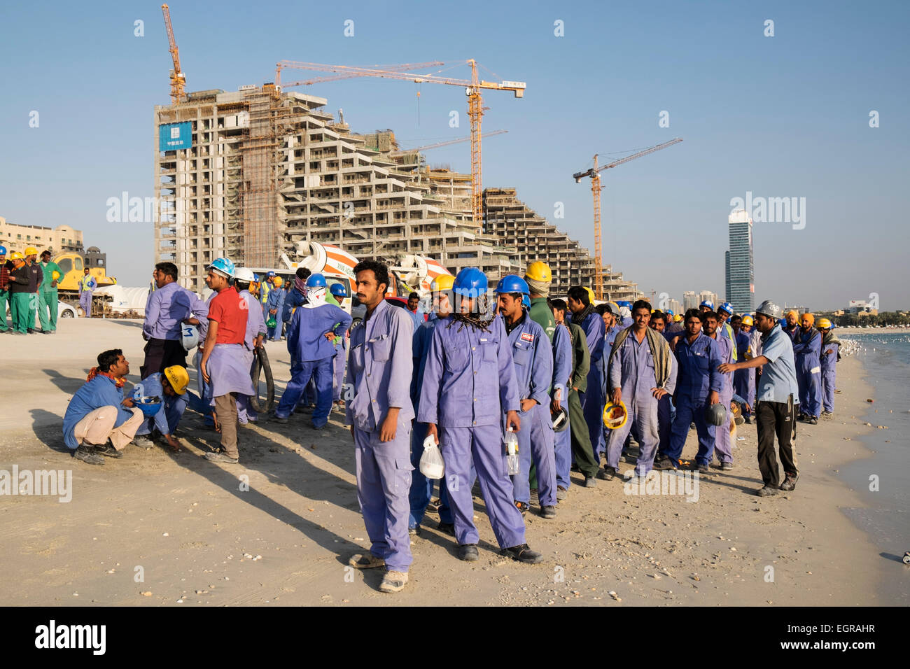 Bauarbeiter, die Schlange, um auf Bus zum Wohnbereich am Ende des Arbeitstages bekommen in Dubai Vereinigte Arabische Emirate Stockfoto