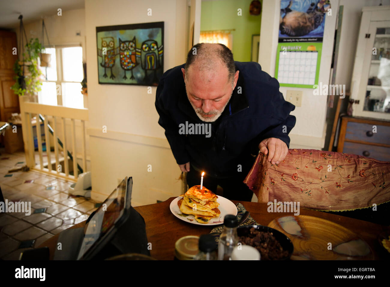 Mann in seinen 50ern Ausblasen der Kerzen auf Geburtstag Pfannkuchen an seinem Geburtstag Stockfoto