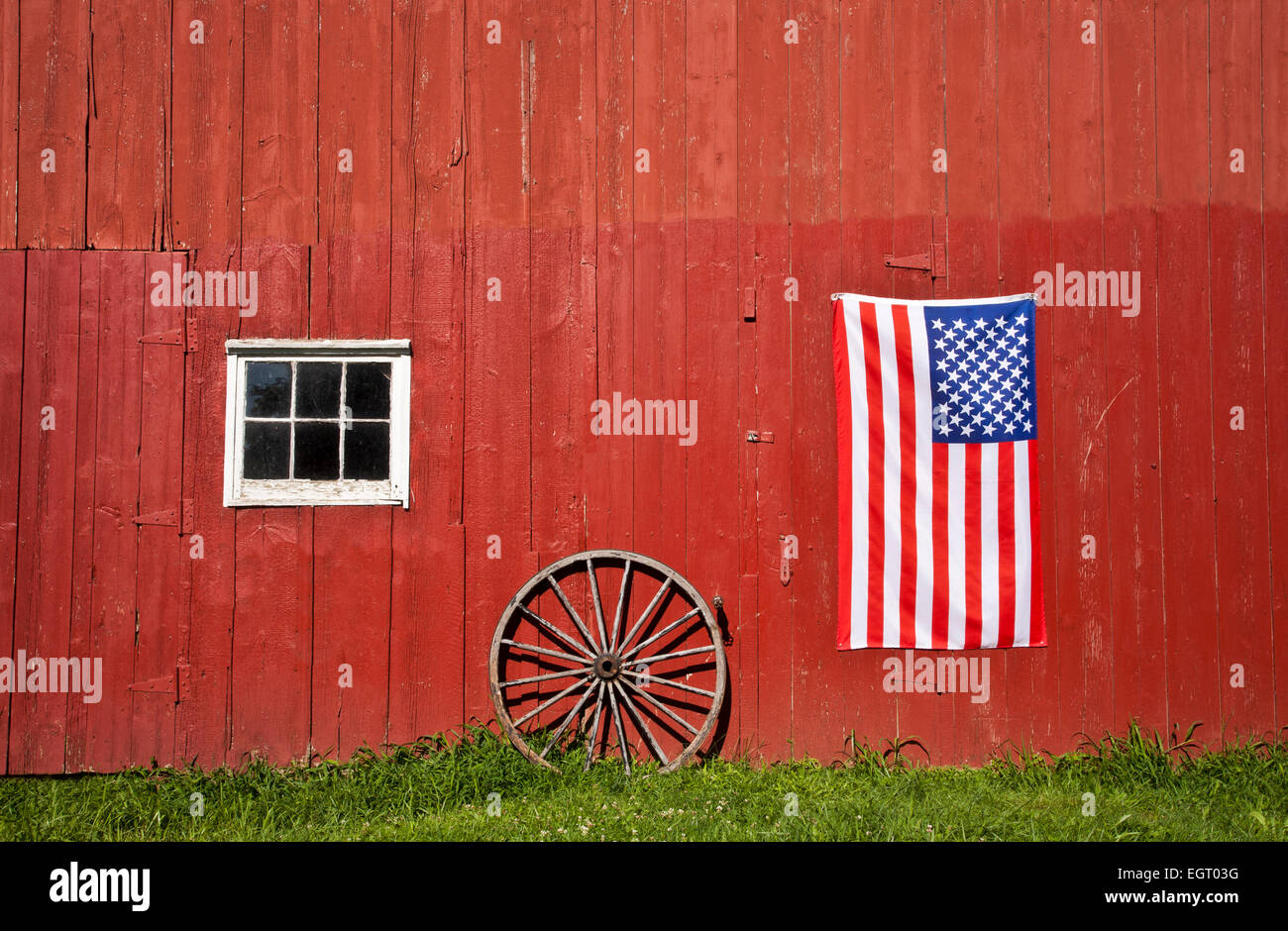 Historische rote Scheune, US-Flagge und ein antikes Wagenrad auf einem Bauernhof, Middlesex County, Monroe Twp., New Jersey, USA, Amerikanisch 10,38 MB, Dt Aug 2013 Stockfoto