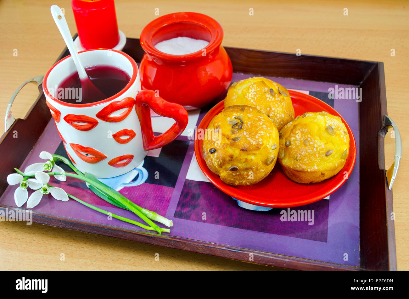 Mais-Brot mit Sesam, Team in einem Lip gemusterten Becher, Zucker und Schneeglöckchen auf einem Tablett, machen ein romantisches Frühstück im Bett Stockfoto