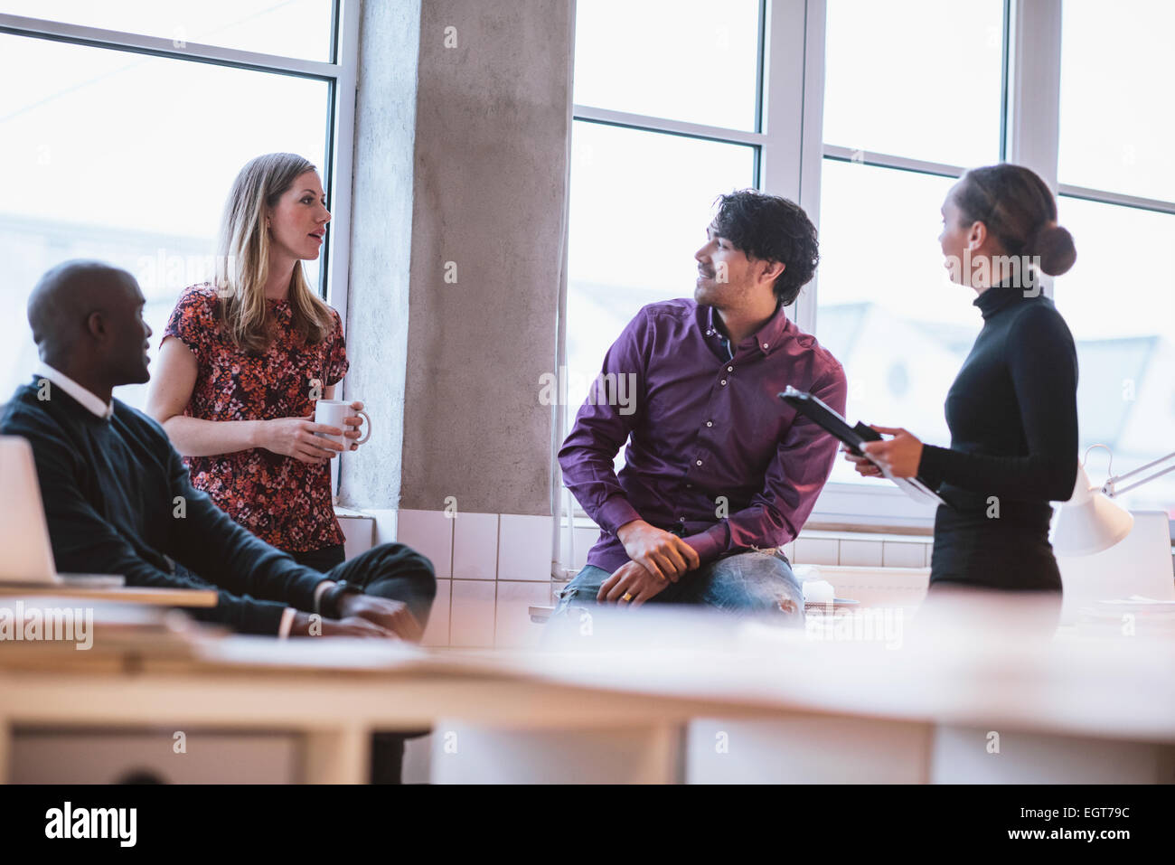 Team junge Berufstätige mit beiläufige Diskussion in Büro. Führungskräfte haben freundliche Diskussion während der Pause. Stockfoto