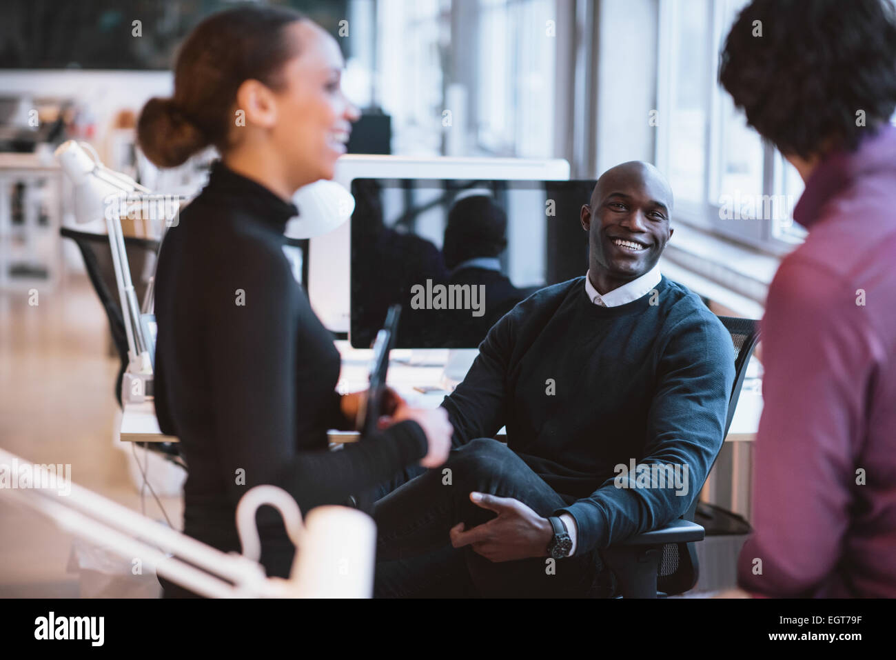 Afrikanische glücklich mit Kollegen lächelnd am Schreibtisch sitzen. Junge Führungskräfte in Pause. Stockfoto