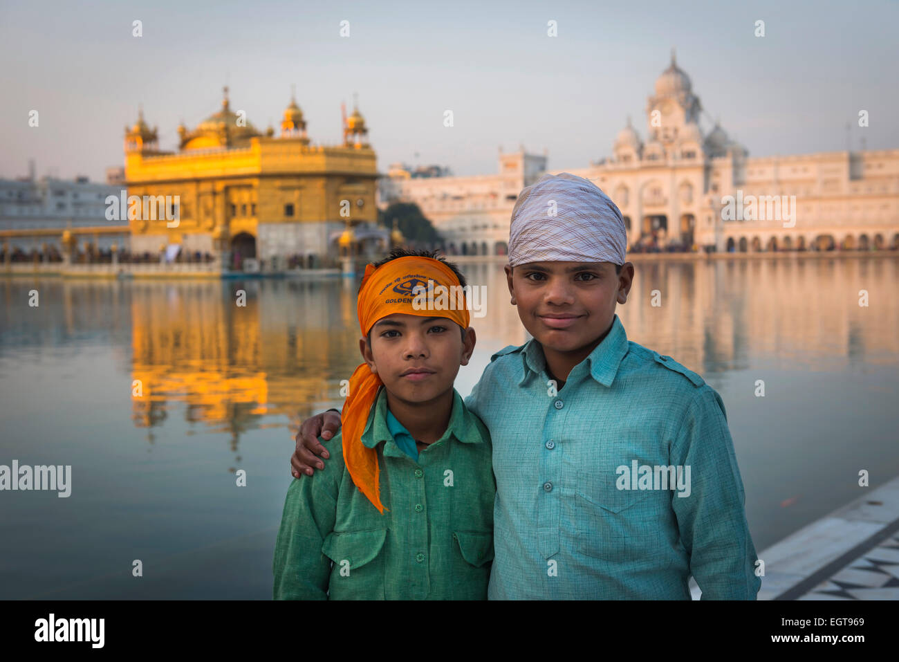 Zwei jungen posieren für ein Foto vor dem The Golden Tempel, Amritsar in der Abenddämmerung. Stockfoto