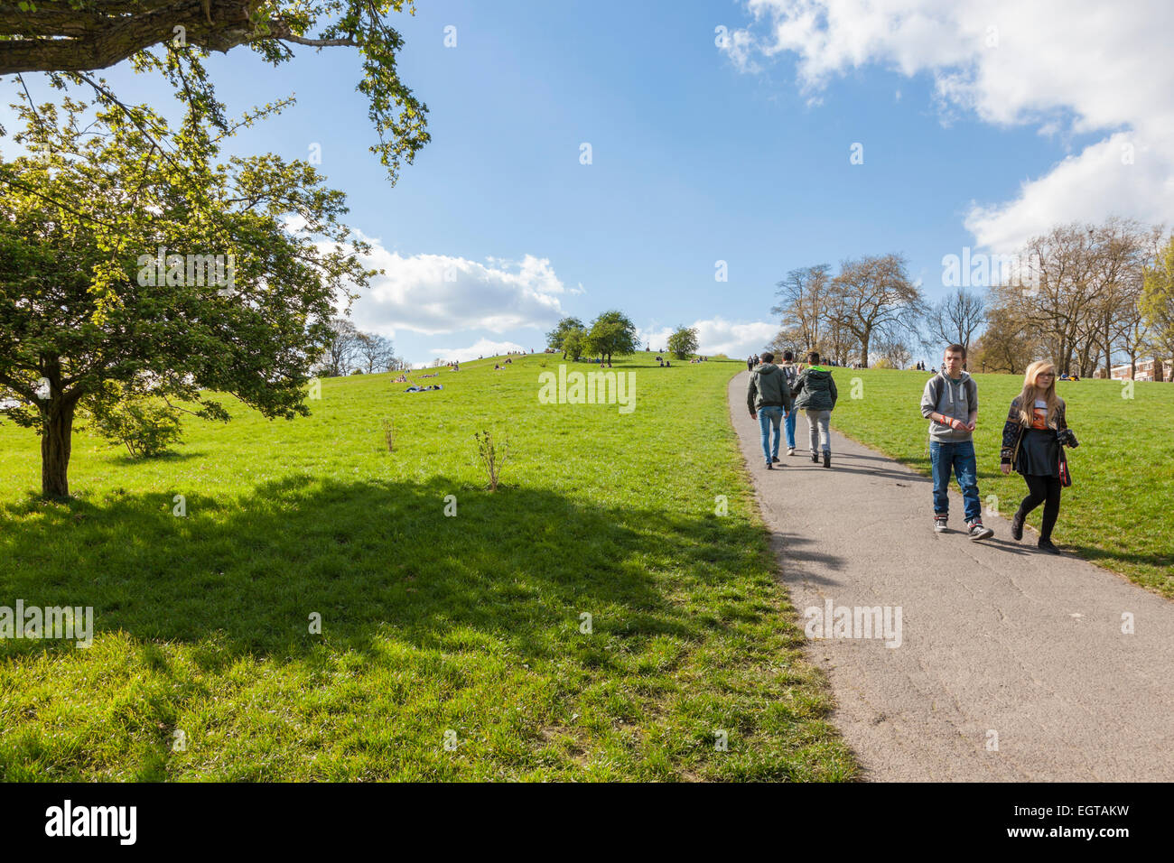 Menschen zu Fuß nach oben und unten einen Hügel in einem Park an einem sonnigen Tag im Frühling. Primrose Hill, London, England, Großbritannien Stockfoto