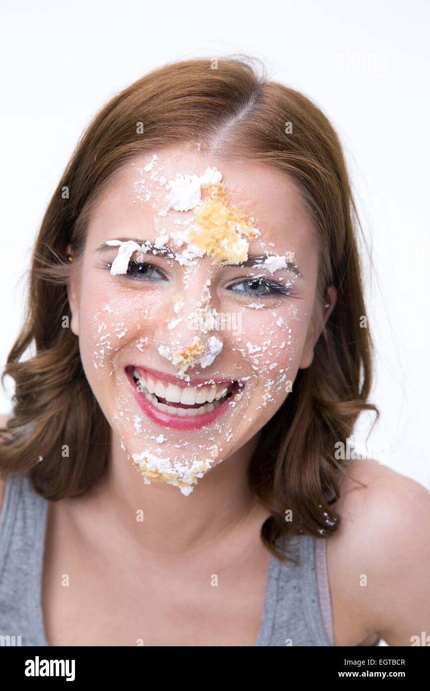 Glückliche junge Frau mit Kuchen auf ihr Gesicht Stockfoto