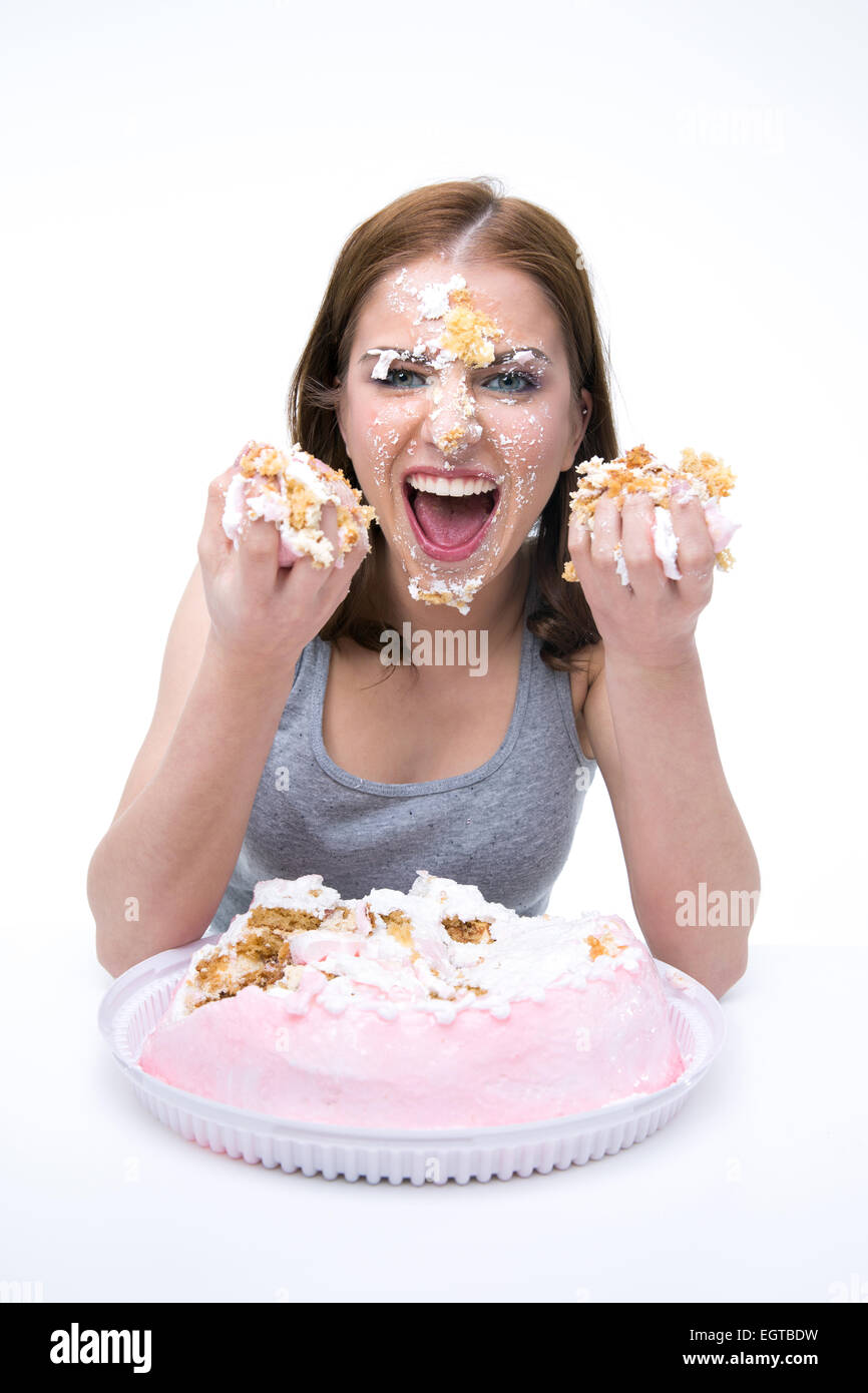 Böse junge Frau sitzt am Tisch mit Kuchen Stockfoto