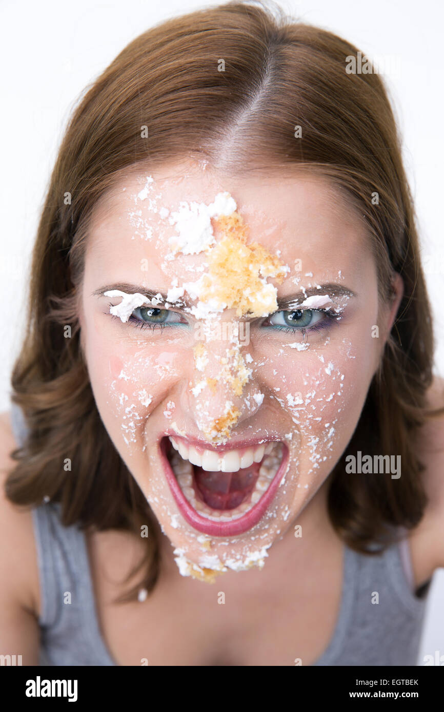 Böse junge Frau mit Kuchen auf ihr Gesicht Stockfoto